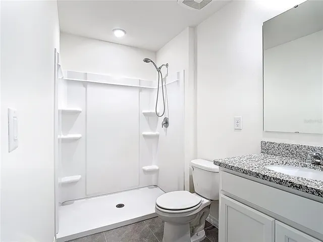 a bathroom with a granite countertop sink a toilet and shower