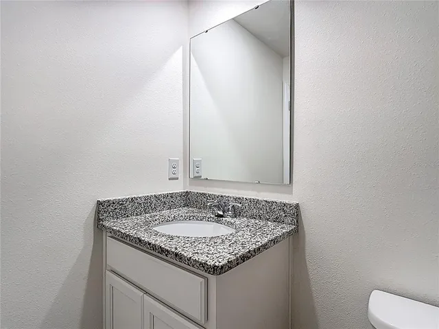 a bathroom with a granite countertop sink and a mirror