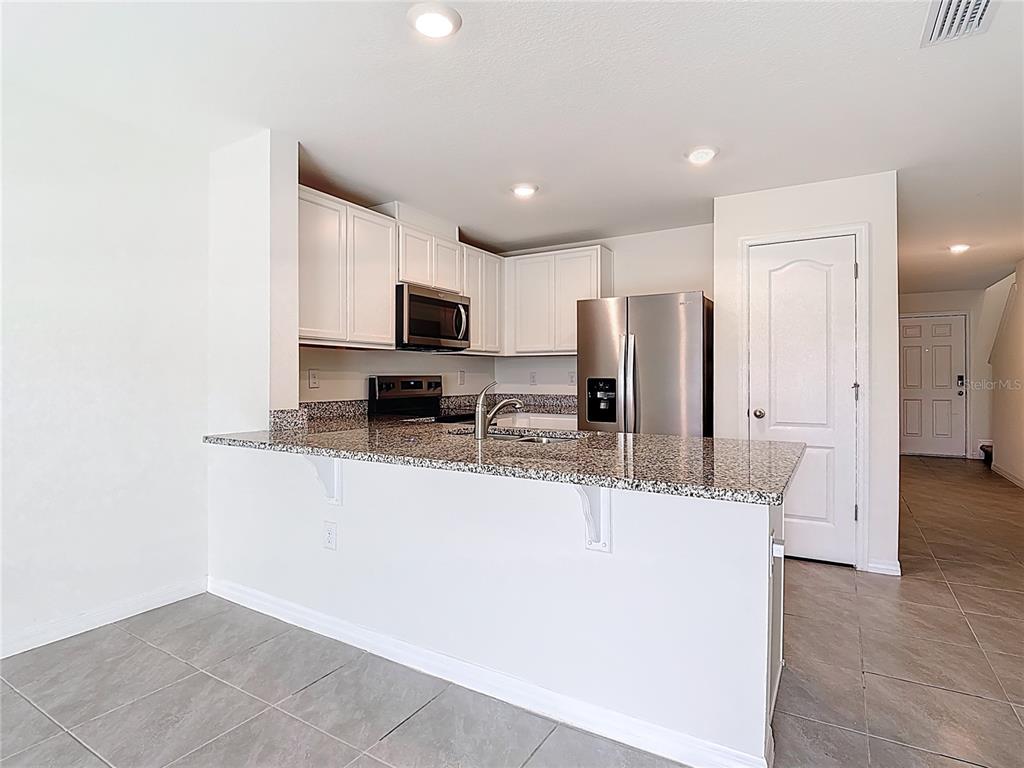 6632 Druid Way St. Cloud, FL 34773 - Photo 7 of 38 a kitchen with kitchen island a sink stainless steel appliances and cabinets
