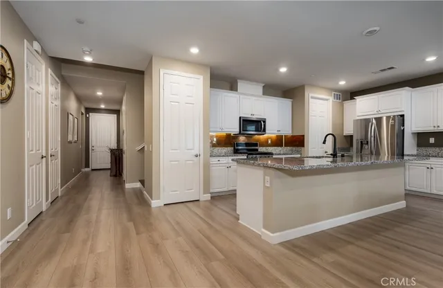 a kitchen with stainless steel appliances granite countertop a refrigerator oven a sink dishwasher and a stove with wooden floor