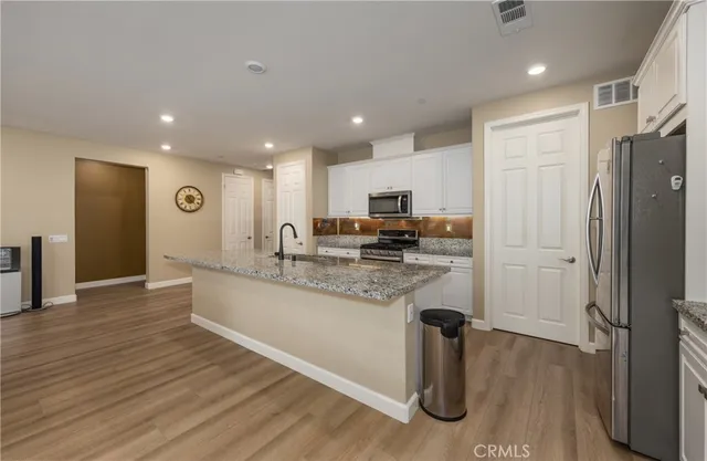 a kitchen with stainless steel appliances granite countertop a refrigerator and a stove top oven