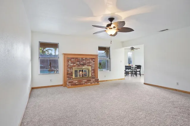 a view of an empty room with chandelier fan and windows