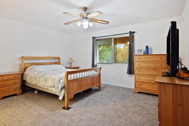 a bedroom with a bed and a flat tv screen on dresser