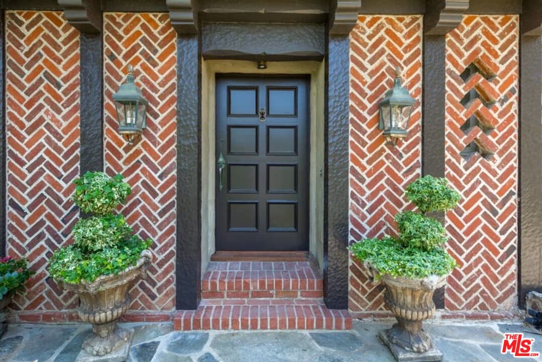 1957 Mandeville Canyon Road Los Angeles, CA 90049 - Photo 6 of 54 a front view of a house with a yard