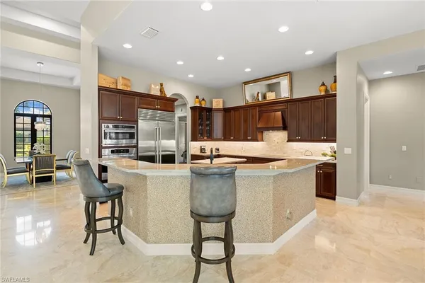 a kitchen with stainless steel appliances granite countertop a kitchen island a stove a sink a dining table and chairs