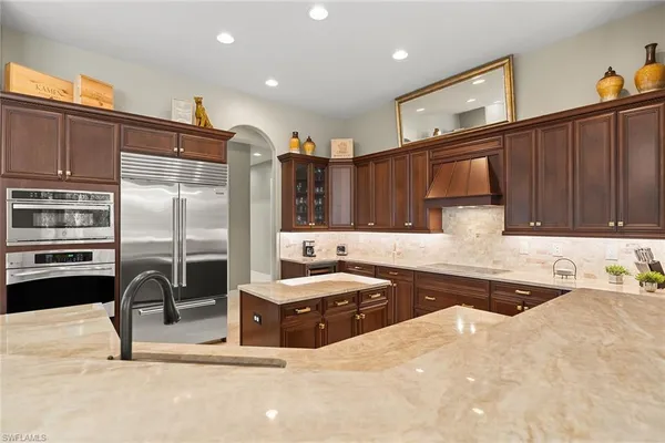 a kitchen with stainless steel appliances kitchen island granite countertop a sink refrigerator and cabinets