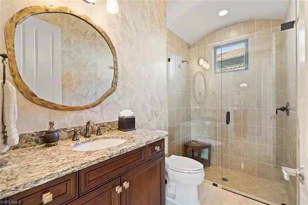 a bathroom with a granite countertop toilet a sink and a mirror