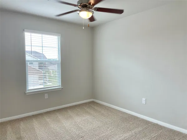 an empty room with a window and a fan