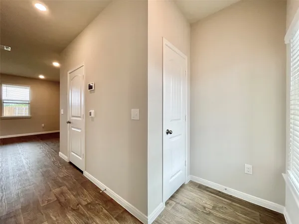 a view of hallway with window and wooden floor