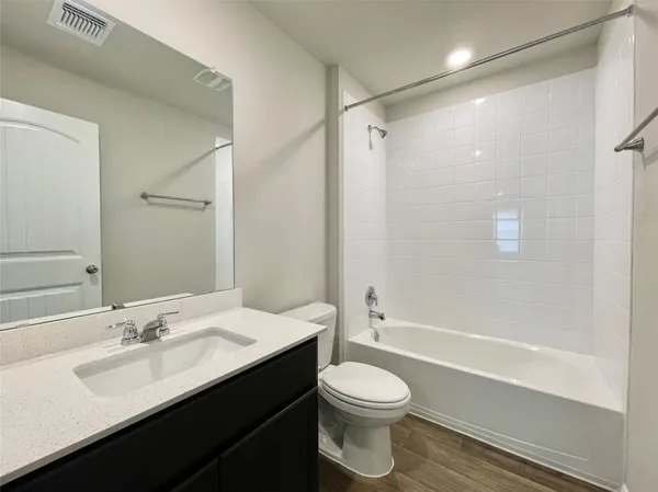 a bathroom with a bathtub shower sink vanity mirror and toilet