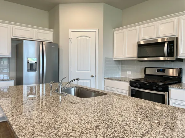 a kitchen with stainless steel appliances granite countertop a stove a microwave and a sink