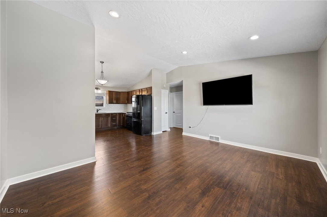 3213-3217 Pickle Road Green, OH 44312 - Photo 14 of 41 Unfurnished living room featuring dark wood finished floors, vaulted ceiling, a textured ceiling, and recessed lighting