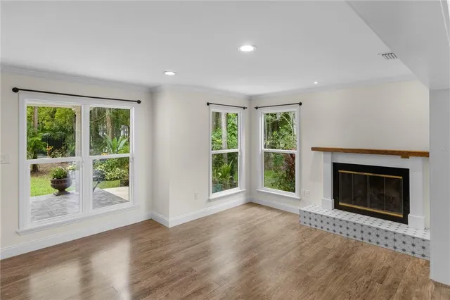 a view of an empty room with window and wooden floor