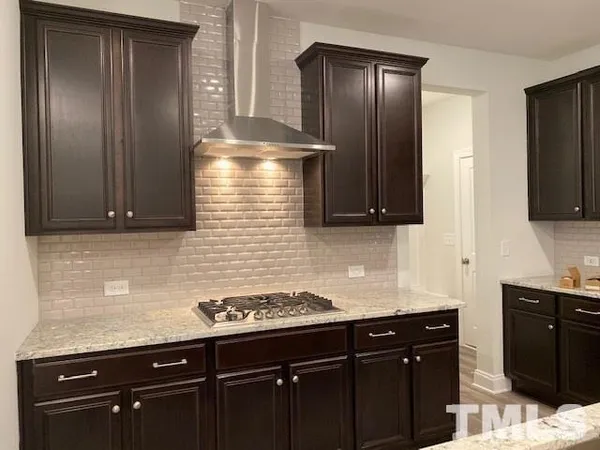 a kitchen with granite countertop stainless steel appliances a sink stove and refrigerator