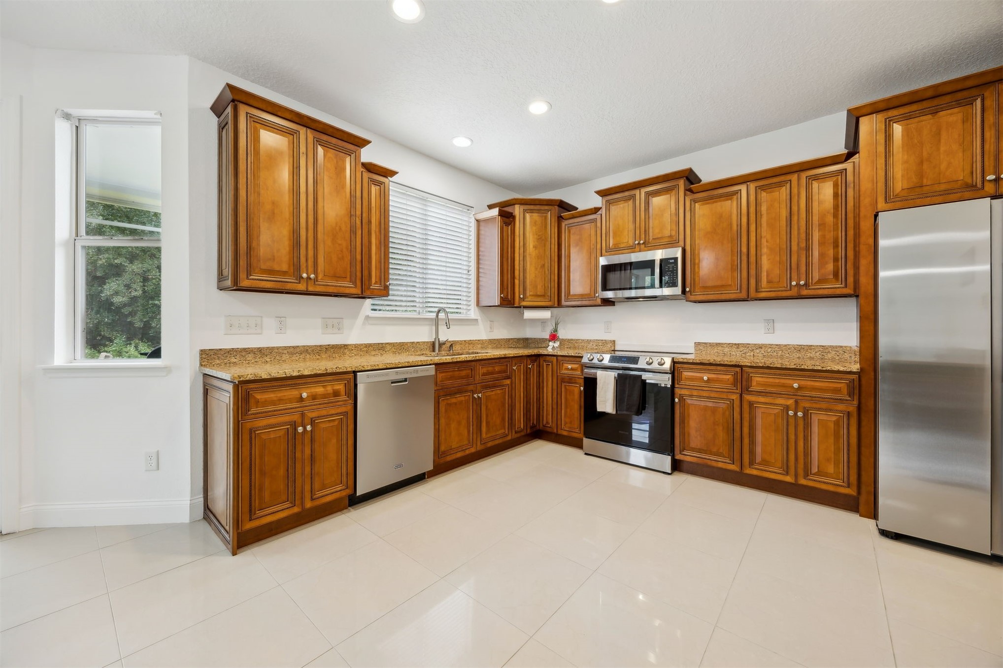 76002 Tideview Lane Yulee, FL 32097 - Photo 16 of 58 a kitchen with stainless steel appliances granite countertop a stove a sink dishwasher a refrigerator and cabinets with wooden floor