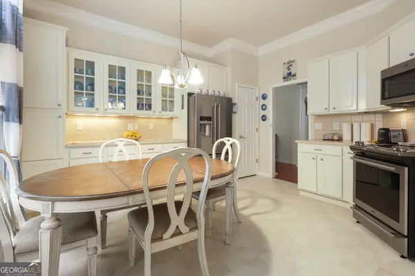 a kitchen with stainless steel appliances kitchen island granite countertop a dining table chairs and a refrigerator