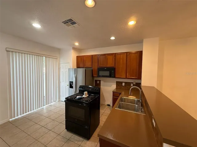 a view of a refrigerator in kitchen and an empty room