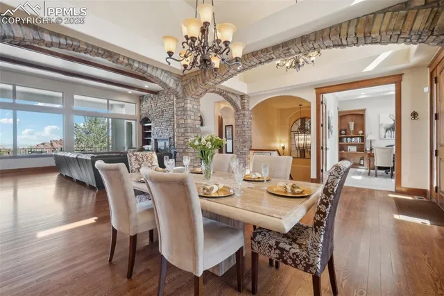 a dining hall with stainless steel appliances granite countertop a kitchen island a stove a sink a couch and a dining table with wooden floor