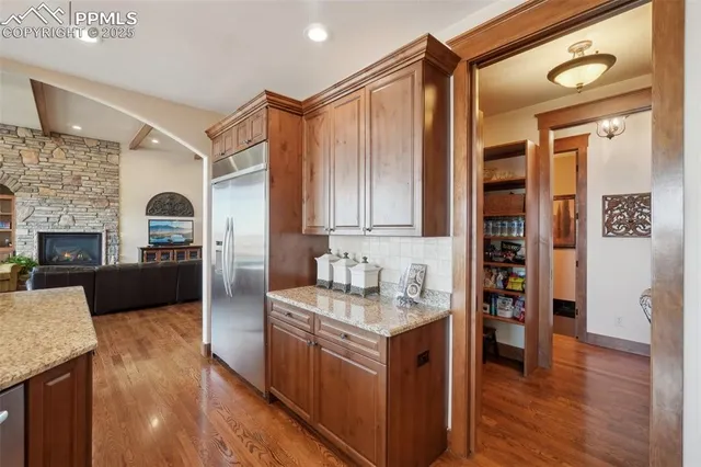 a kitchen with stainless steel appliances granite countertop a refrigerator a stove top oven and a wooden floors