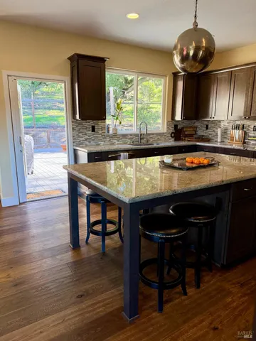 a kitchen with stainless steel appliances granite countertop wooden floors a stove a sink and a microwave