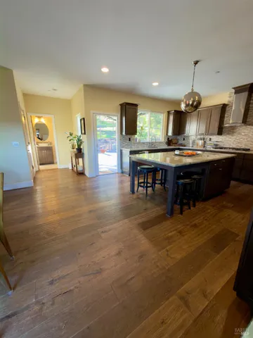 a kitchen with stainless steel appliances granite countertop a sink dishwasher and a dining table with wooden floor