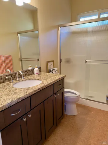 a bathroom with a granite countertop sink a toilet and a mirror