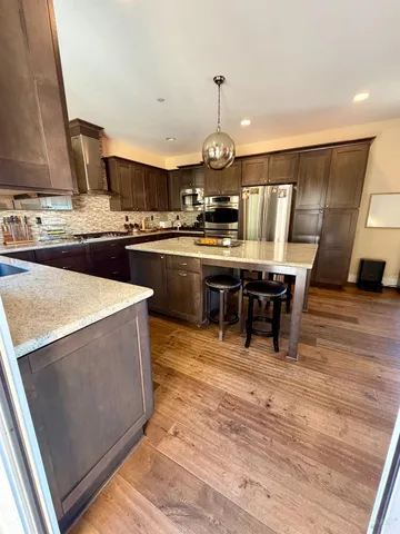 a kitchen with stainless steel appliances a stove a sink dishwasher and a dining table with wooden floor
