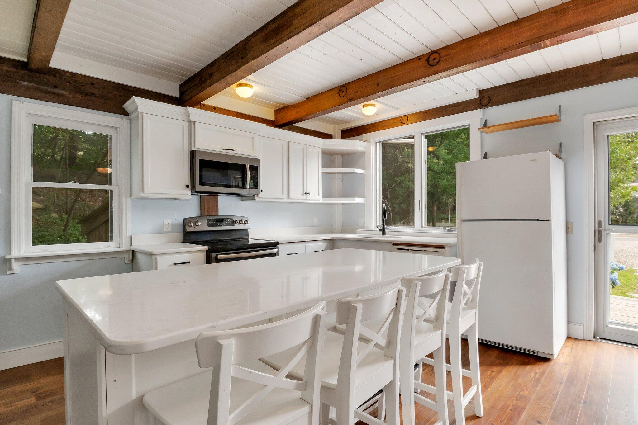 36 Bakers Pond Road Orleans, MA 02653 - Photo 25 of 50 a kitchen with stainless steel appliances granite countertop a stove a refrigerator a microwave a sink and white cabinets with wooden floor