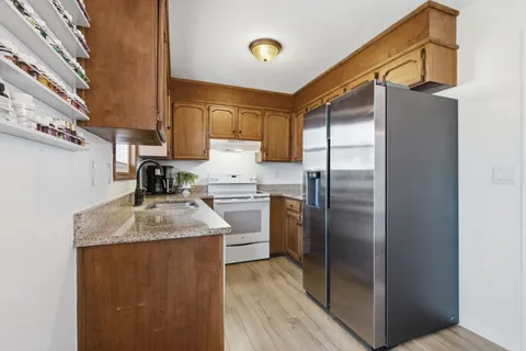 a kitchen with stainless steel appliances granite countertop a sink and a refrigerator