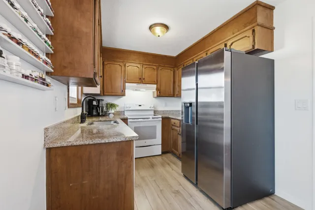 a kitchen with stainless steel appliances granite countertop a sink and a refrigerator