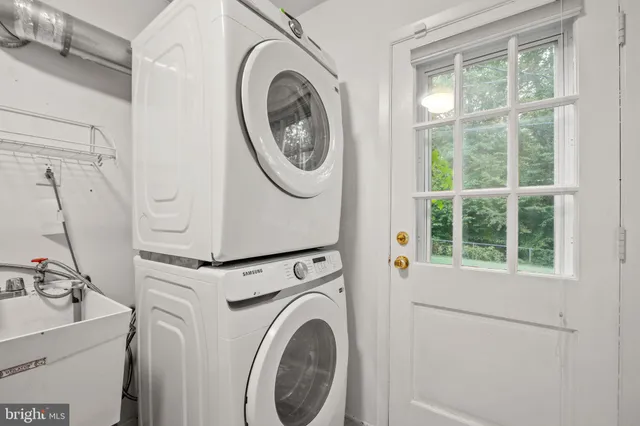 a view of a patio with couches table and chairs under an umbrella with a small yard
