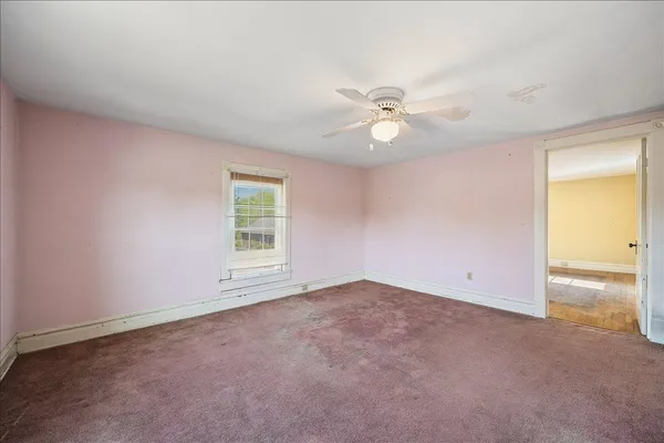 an empty room with a window and a ceiling fan