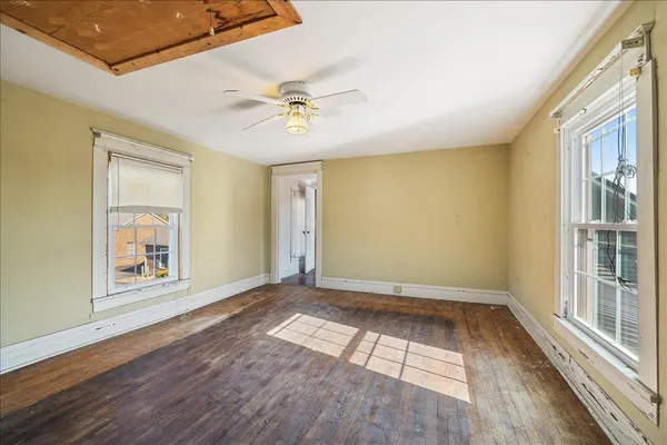 a view of empty room with wooden floor and fan