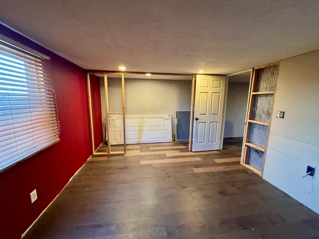 a view of empty room with wooden floor and window