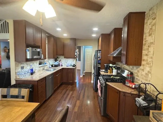 a kitchen with stainless steel appliances kitchen island granite countertop a stove refrigerator and cabinets