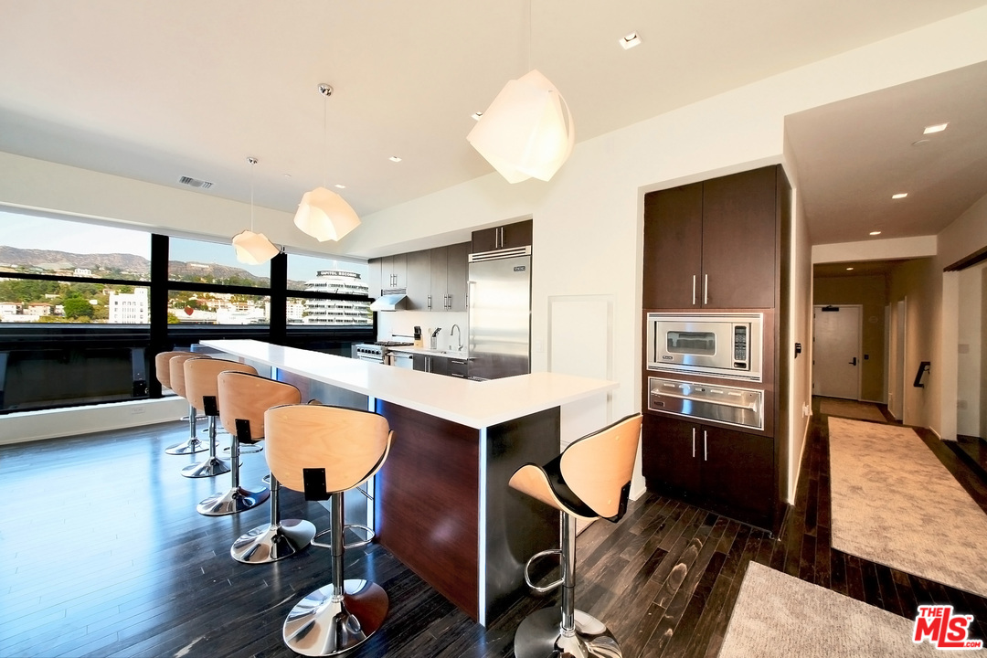 1645 Vine Street, Unit 908 Los Angeles, CA 90028 - Photo 16 of 52 a kitchen with stainless steel appliances kitchen island granite countertop a sink refrigerator and cabinets