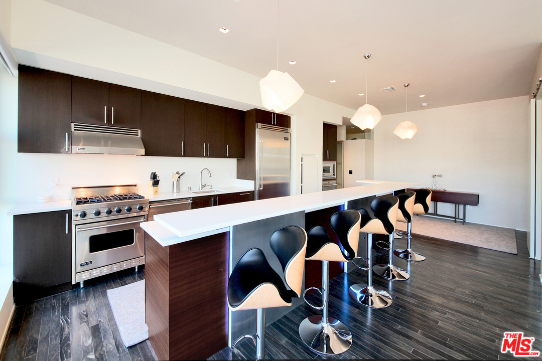 1645 Vine Street, Unit 908 Los Angeles, CA 90028 - Photo 20 of 52 a kitchen with stainless steel appliances a dining table chairs stove and cabinets