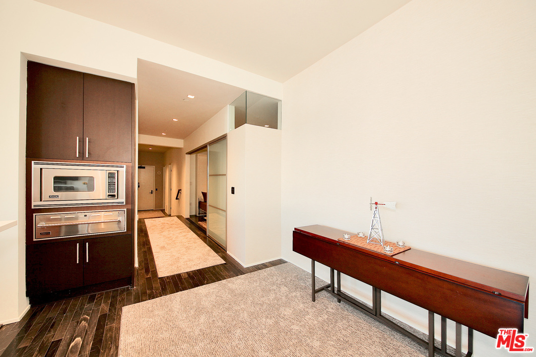 1645 Vine Street, Unit 908 Los Angeles, CA 90028 - Photo 25 of 52 a living room with stainless steel appliances kitchen island granite countertop a refrigerator a stove and a sink with wooden cabinets