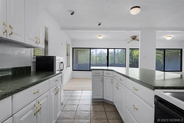 a large white kitchen with a large window and stainless steel appliances