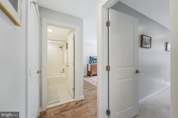 a view of a hallway with wooden floor and a bathroom
