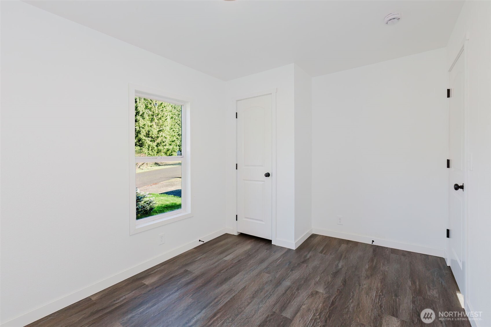 3371 Southeast Bielmeier Road, Unit 78 Port Orchard, WA 98367 - Photo 12 of 27 a view of an empty room with wooden floor and a window