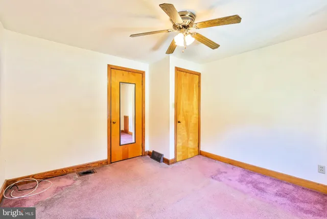 an empty room with a ceiling fan and carpet