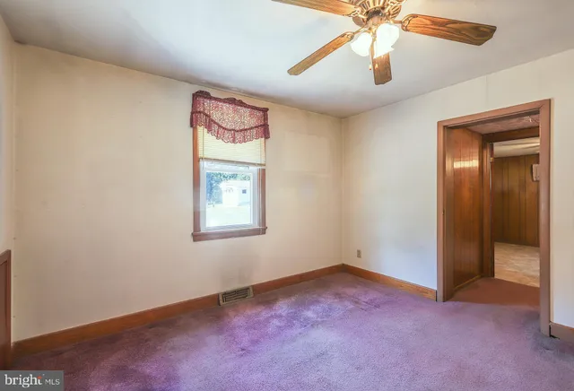 an empty room with a chandelier fan and windows