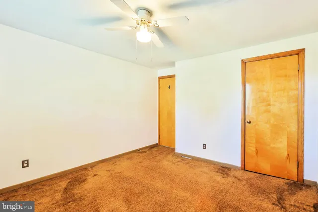 an empty room with a ceiling fan and a window