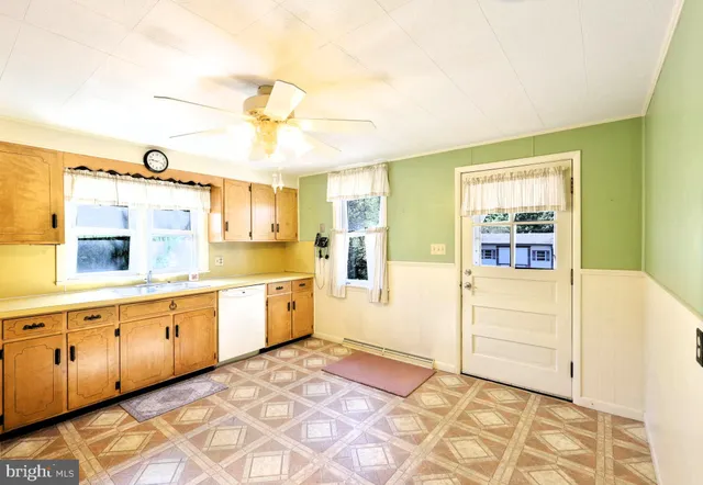 a large white kitchen with cabinets a sink and dishwasher