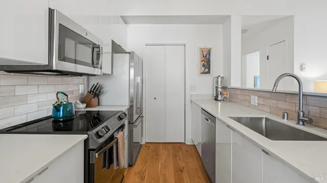 a kitchen with stainless steel appliances granite countertop a sink a stove and wooden cabinets