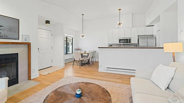 a living room with stainless steel appliances furniture a rug and a kitchen view