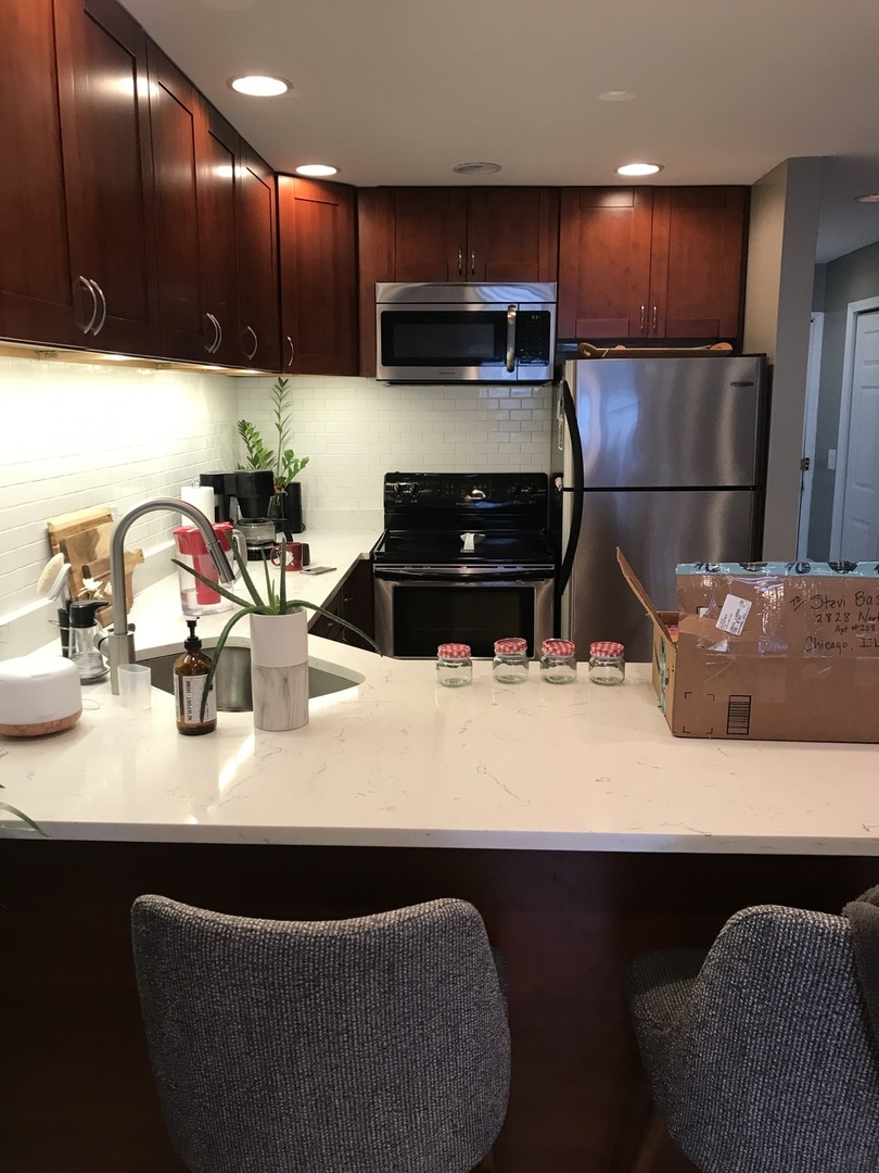 2828 North Burling Street, Unit 208 Chicago, IL 60657 - Photo 2 of 5 a kitchen with kitchen island granite countertop a sink a stove and a refrigerator