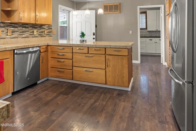 a kitchen with stainless steel appliances granite countertop a stove a sink and a refrigerator with wooden floors