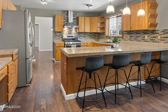 a kitchen with stainless steel appliances granite countertop table chairs sink and wooden floor